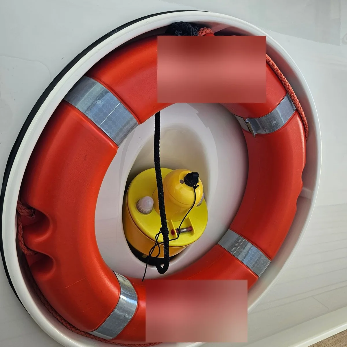 A lifebuoy stowed in a round recess in the superstructure, with a light and smoke unit inside the ring. The lettering on the lifebuoy is blurred.